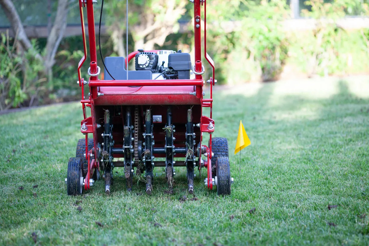 Green yard with professional and. commercial aerator in yard next to yellow marker flag..